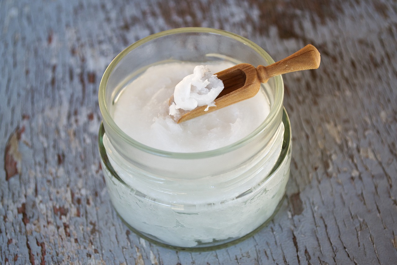 Coconut oil on a wooden spoon. Coconut oil in a glass jar.